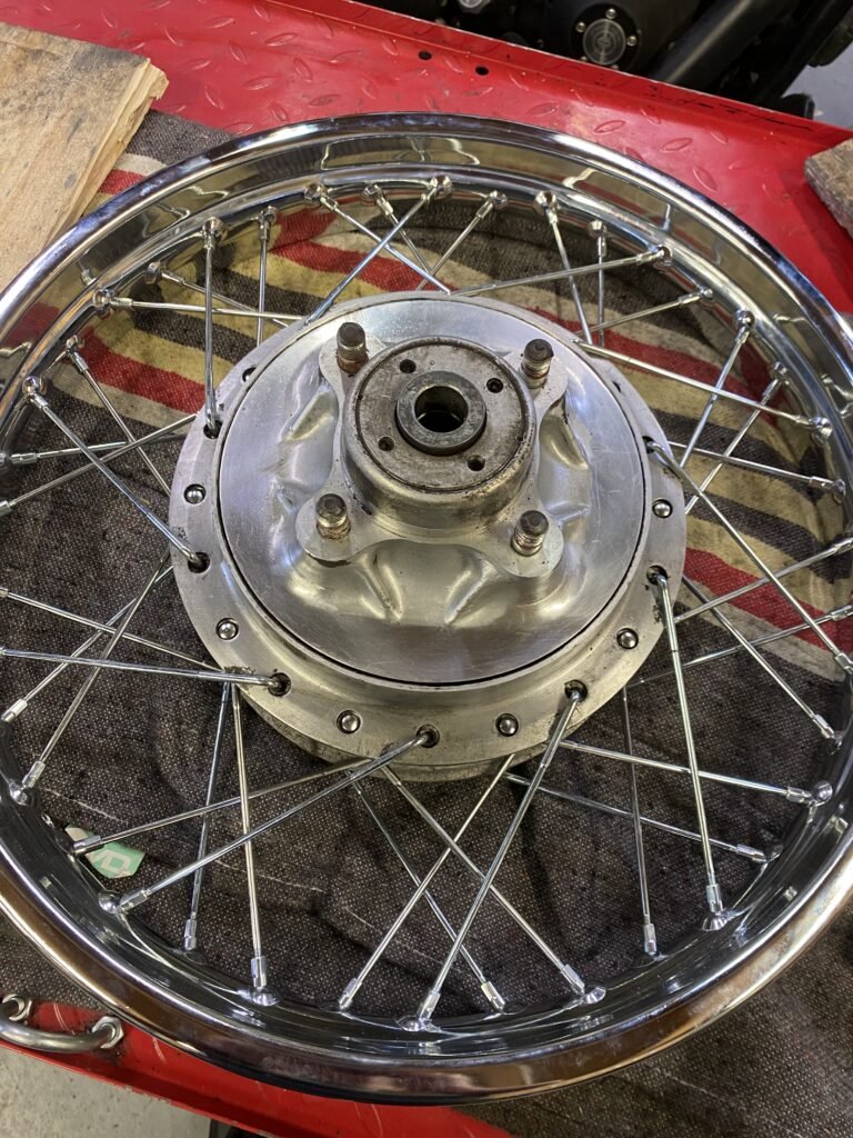 Roue à rayons chromée de Honda 750 Four de 1979 posée sur l'établi de l'atelier