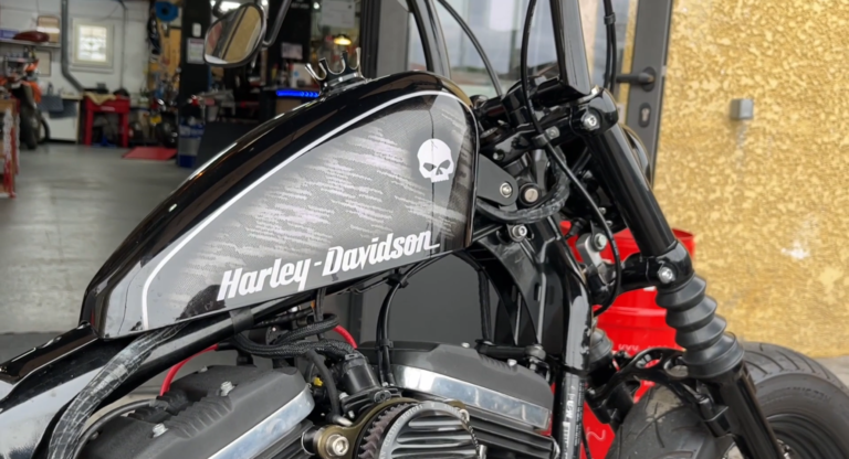 Réservoir Harley-Davidson noir à décor tête de mort, moto garée dans l'atelier